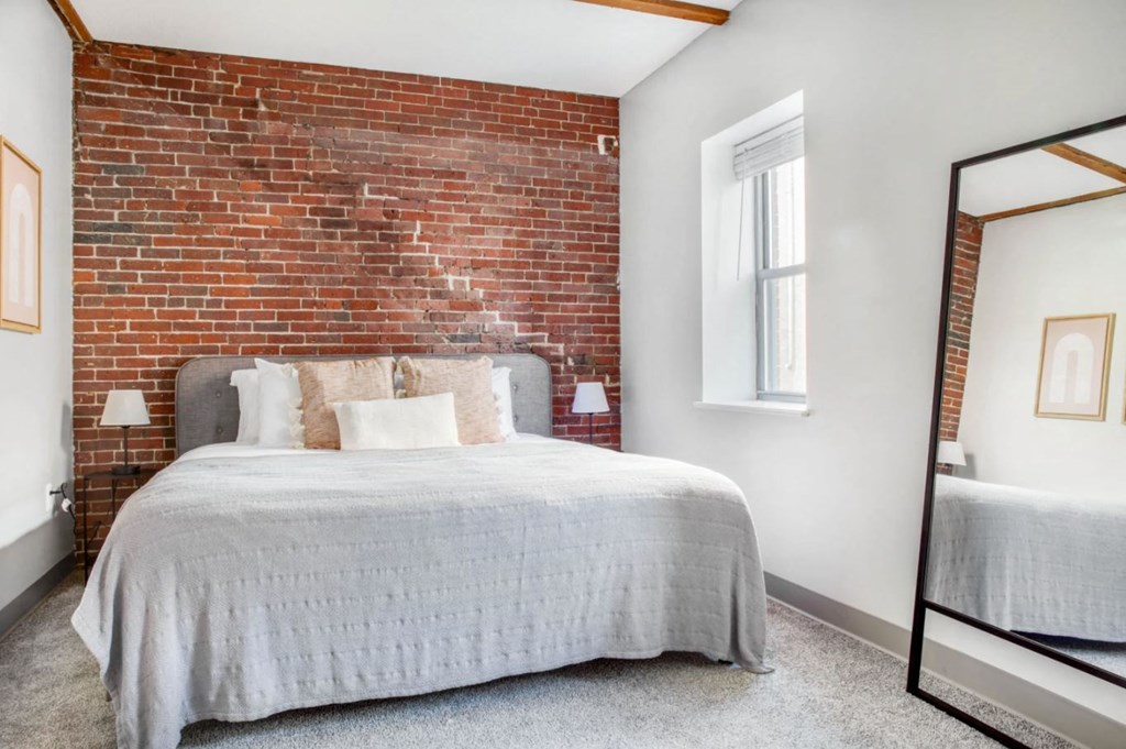 a bedroom with a bed and a brick wall